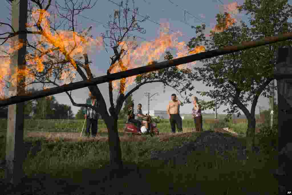 Local residents watch the flames from a damaged gas pipe that was hit by a mortar bomb, during fighting between Ukrainian government troops and pro-Russian militants, outside Slovyansk, eastern Ukraine, May 19, 2014.&nbsp;