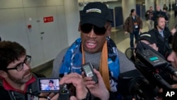 Former NBA star Dennis Rodman, center, arrives at the capital airport for a flight to North Korea, in Beijing, China, Thursday, Dec. 19, 2013.