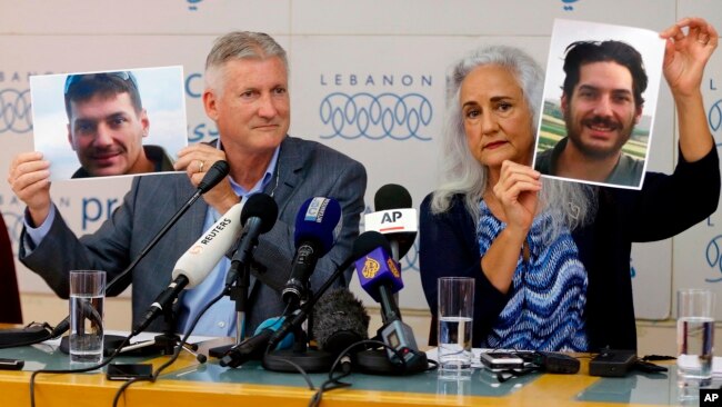 FILE - Marc and Debra Tice, the parents of Austin Tice, who has been missing in Syria since August 2012, hold up photos of him during a news conference at the Press Club in Beirut, Lebanon, July 20, 2017.