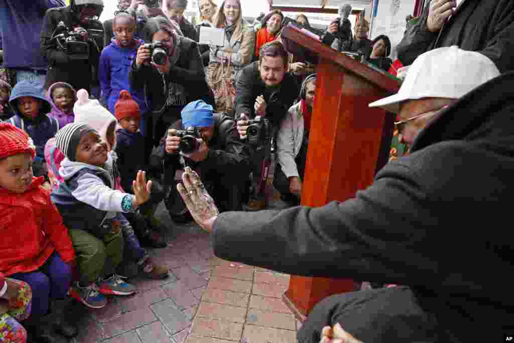 Archbishop Desmond Tutu, right, holds out his hand as he interacts with children during celebrations of former South African President Nelson Mandela&#39;s birthday in Cape Town, South Africa, July 18, 2014.
