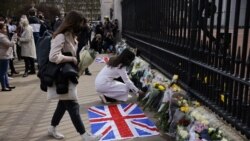 People add flowers to the tributes laid at the railings at the front of Buckingham Palace in central London on April 9, 2021 after the annoucement of the death of Britain's Prince Philip, Duke of Edinburgh.