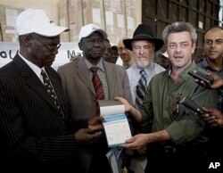 Eamon Omordha, right, Deputy Director of the UN Integrated Referendum and Electoral Division, hands over a referendum ballot to Justice Chan Reec Madut, left, Chairman of the Southern Sudan Referendum Bureau, during a material handover ceremony in Juba 23