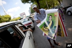 FILE - A street vendor unfolds pages of a calendar featuring Aung San Suu Kyi in a Yangon street, Myanmar, Nov. 12, 2015.