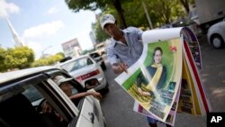 A street vender unfolds pages of a calendar featuring Myanmar's opposition leader Aung San Suu Kyi in a Yangon street, Myanmar, Nov. 12, 2015. 