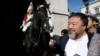 Artist Ai Weiwei passes a member of the Household Cavalry on duty outside Horse Guards Parade as he walks through central London, Sept. 17, 2015.