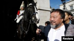 Artist Ai Weiwei passes a member of the Household Cavalry on duty outside Horse Guards Parade as he walks through central London, Sept. 17, 2015.