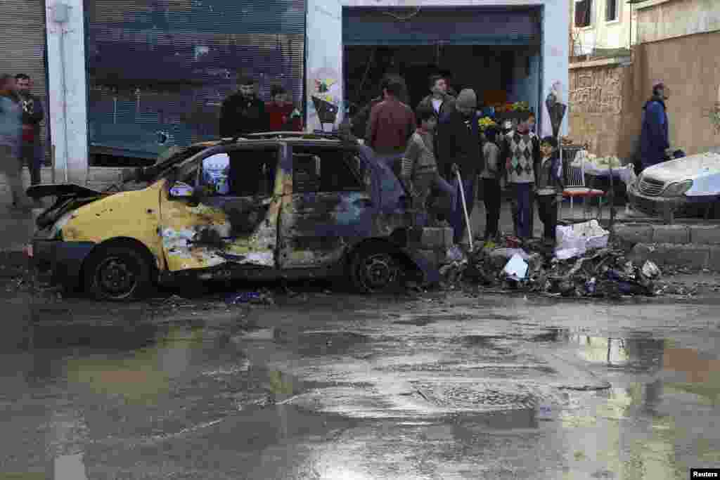 Warga memeriksa kerusakan yang disebabkan oleh bom bunuh diri yang dilakukan oleh organisasi Negara Islam Irak dan Levant di markas Brigade Tauhid dan Brigade Al-Fateh di Aleppo, 12 Januari 2014. 