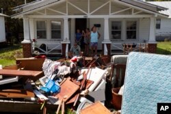 Residentes de New Bern, Carolina del Norte, se asoman a la entrada de sus casas para ver pasar al presidente Donald Trump, que visitó algunas zonas afectadas por el huracán Florence. Sep. 19 de 2018.