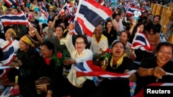 Protesters wave Thai national flags as their leaders appear on stage during a protest in central Bangkok on November 1, 2013.