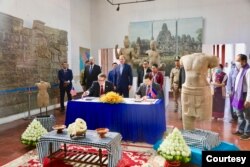 មន្ត្រី​តំណាង​ស្ថានទូត​សហរដ្ឋអាមេរិក​និង​មន្ត្រី​តំណាង​ក្រសួង​វប្បធម៌​និង​វិចិត្រ​សិល្បៈ​ចូលរួម​ក្នុង​ពិធី​ប្រគល់​រូបបដិមា​ខ្មែរ​ចំនួន​ពីរ ​ដែល​ស្ថានទូត​សហរដ្ឋអាមេរិក​ប្រគល់​ជូន​កម្ពុជា​វិញ ក្រោយ​ពី​រឹបអូស​បាន​កាល​ពី​ឆ្នាំ​២០០៥​និង​២០១៧​នៅ​សហរដ្ឋអាមេរិក ថ្ងៃ​ទី​៣ ខែមេសា ឆ្នាំ​២០២០។ (រូបថត​ផ្ដល់​ឲ្យ​ដោយ​ស្ថានទូត​អាមេរិក)