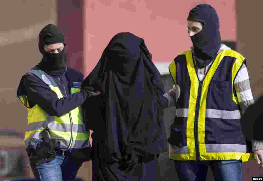 Masked Spanish police officers lead a detained woman in Melilla. Spanish and Moroccan police have arrested seven people in an ongoing joint sweep of suspected efforts to recruit women to go to Syria and Iraq to support Islamic State insurgents, the Spanish Interior Ministry said.