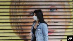 Arhiv - Žena nosi masku dok prolazi pored zatvorene prodavnice u Londonu, 29. april 2020.