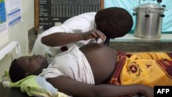 FILE - A health care worker attends to a pregnant woman in Mbale district, eastern Uganda, Sept. 27, 2011.
