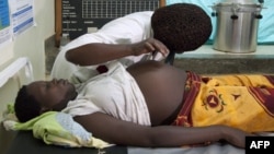 FILE - Agnes Masagwoy, a worker of the Health Care center IV of Busiu in Mbale district, eastern Uganda, attends to Mary Watera, who is pregnant with her first baby.