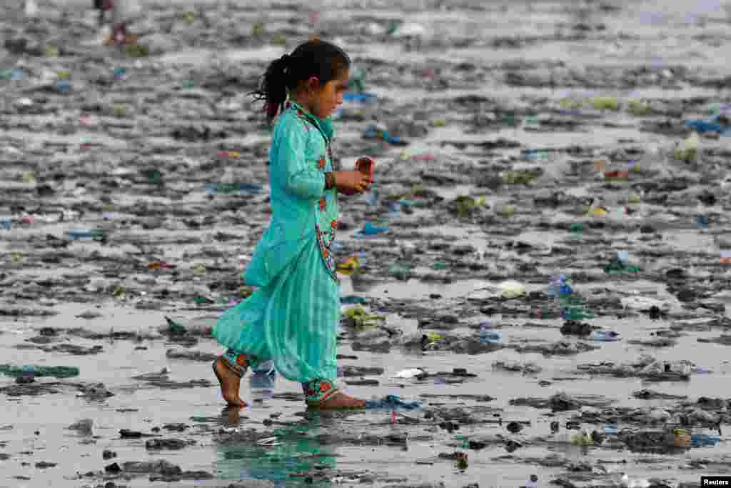 A girl walks through rubbish left by sea waves along Clifton beach in Karachi, Pakistan.