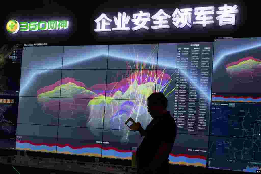 A worker is silhouetted against a computer display showing a live visualization of the online phishing and fraudulent phone calls across China during the 4th China Internet Security Conference in Beijing.