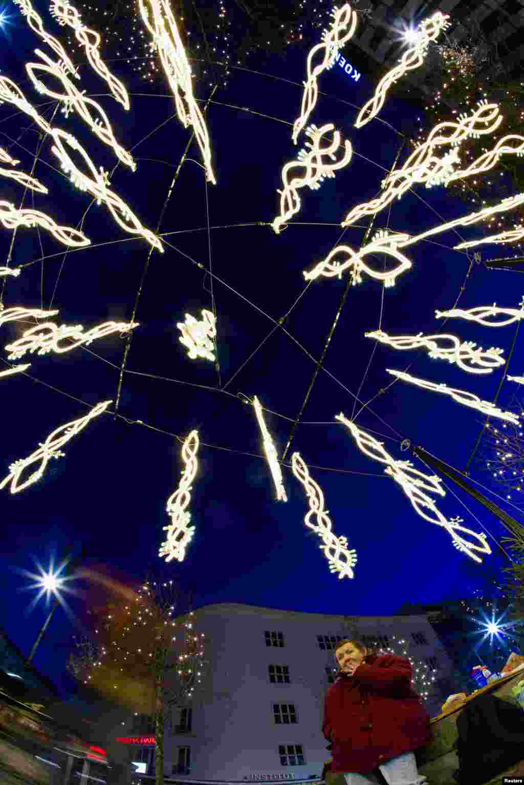 A woman sits underneath a New Year celebrations light installation as her son (not pictured) asks drivers for money at Kurfuerstendamm in Berlin, Germany.