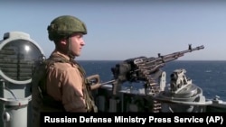 FILE - A Russian seaman stands next to a machine gun on the Russian missile cruiser Moskva, near the shore of Syria’s province of Latakia, Syria, Nov. 27, 2015.
