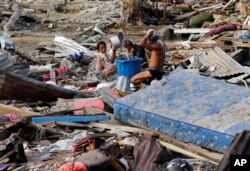 Residents take a bath amid remains of toppled homes and structures at the earthquake and tsunami-hit Palu, Central Sulawesi, Indonesia, Oct. 5, 2018.