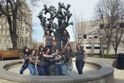 In this March 14, 2020 photo provided by Jaimie Kirkpatrick, Boston College seniors pop champagne beside the Tree of Life sculpture on the school's campus in Boston.