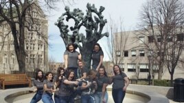 In this March 14, 2020 photo provided by Jaimie Kirkpatrick, Boston College seniors pop champagne beside the Tree of Life sculpture on the school's campus in Boston.