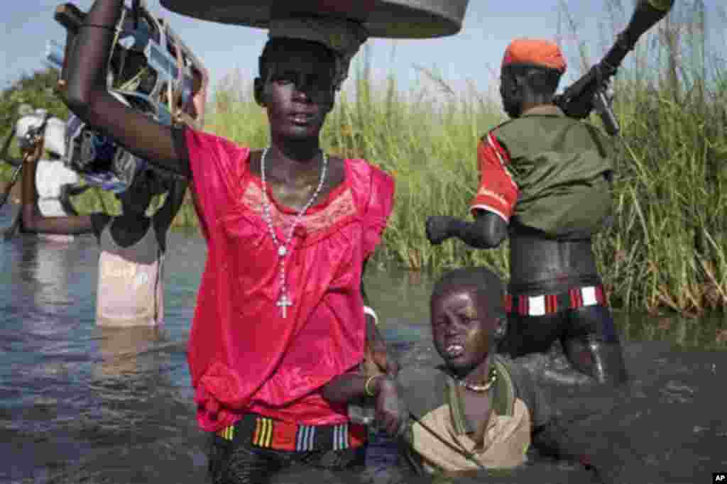 Une famille de l&rsquo;ethnie Nuer à la recherche des mécadiments et de la nourriture, mais qui doit regagner leur village dans la zone contrôlée par des rebelles, prépare d&rsquo;embarquer dans un canoë pour traverser une zone inondée où elle sera contrainte de marcher dans le marécage près de la Mission Onusienne au Sud Soudan (UNMISS) au village de Bentiu, au Sud Soudan. 