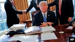 FILE - President Donald Trump sits at his desk after a meeting in the Oval Office of the White House in Washington, Feb. 8, 2017. A recent tweet by Trump referring to "tapes" of conversations with James Comey has sparked talk of the existence of a secret recording system in the White House.