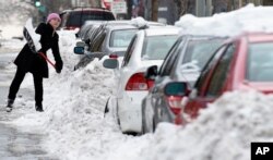 Grace McGuire of Washington shovels out her car in Washington, Jan. 26, 2016, as the nation's capital digs out following a monster weekend snow.