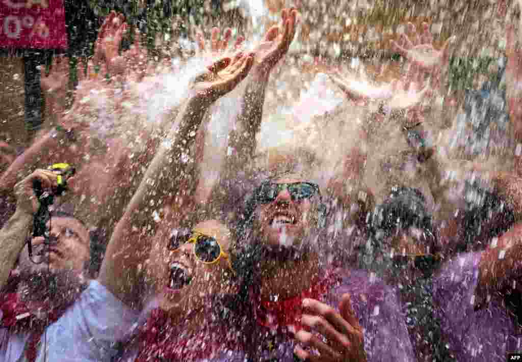 6 tháng 7: Thủ tục xối nước từ bao lơn xuống đầu những người đến dự lễ hội San Fermin ở Pamplona, bắc Tây Ban Nha. Lễ hội kéo dài 9 ngày thu hút hàng vạn người đến tham gia các trò chơi như đuổi bò, đấu bò. (AP Photo/Alvaro Barrientos)