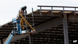 This July 1, 2019, photo shows a construction worker atop a new building in Hillsborough, N.C. On Tuesday, Oct. 1, the Commerce Department reports on U.S. construction spending in August. (AP Photo/Gerry Broome)