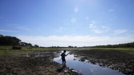 Cristopher Benegas, 12, fishes in what's left of the Payagua stream, a tributary of the Paraguay River, in Chaco I, Paraguay, early Friday, Aug. 27, 2021. (AP Photo/Jorge Saenz)