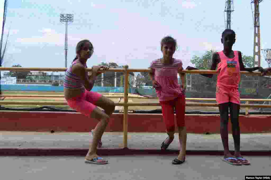 Three young Cuban girls prepare for track practice outside Mayabeque baseball stadium.