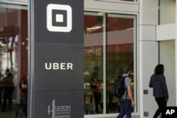 FILE- People make their way into the building that houses the headquarters of Uber, June 21, 2017, in San Francisco.