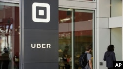 FILE - People make their way into the building that houses the headquarters of the ride-hailing company Uber, June 21, 2017, in San Francisco, California.