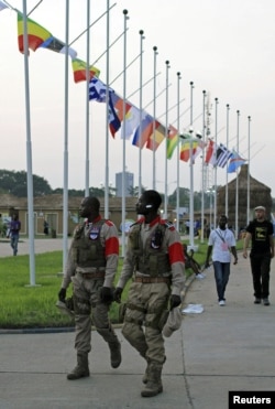 Security guards walk past national flags at dusk at the Francophone Summit in the Democratic Republic of Congo's capital Kinshasa, October 10, 2012.