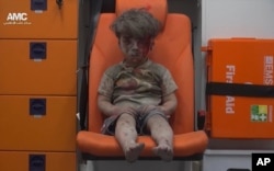 In this frame grab taken from video provided by the Syrian anti-government activist group Aleppo Media Center (AMC), a child sits in an ambulance after being pulled out or a building hit by an airstirke, in Aleppo, Syria, Aug. 17, 2016.