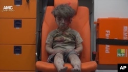 မျက်နှာမှာ ဖုံတွေ၊ သွေးတွေ ပေကျံနေတဲ့ ကလေးငယ်လေး အရေးပေါ် လူနာတင် ယာဉ်ကားထဲ ထိုင်နေတဲ့ပုံ
