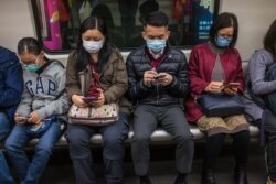 People wear masks on a train on the first day of the Lunar New Year of the Rat in Hong Kong on January 25, 2020, as a preventative measure following a coronavirus outbreak which began in the Chinese city of Wuhan.