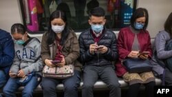 People wear masks on a train on the first day of the Lunar New Year of the Rat in Hong Kong on January 25, 2020, as a preventative measure following a coronavirus outbreak which began in the Chinese city of Wuhan.