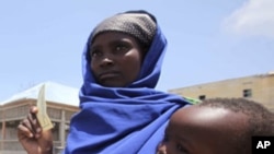 An internally displaced Somali woman carries her child as they wait to receive food aid at a distribution centre at Badbaado settlement camp in Somalia's capital Mogadishu, August 18, 2011