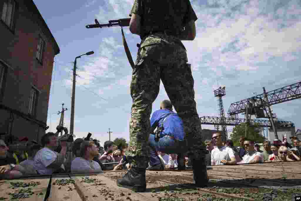 Vyacheslav Ponomarev (center in blue), the self-proclaimed mayor of Slovyansk, speaks to local citizens while his armed bodyguard remains behind him, in Slovyansk, eastern Ukraine, Tuesday, May 20, 2014.