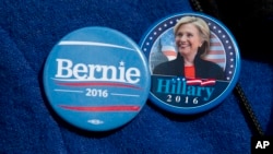 Algunos votantes demócratas usan distintivos de ambos candidatos a la nominación presidencial, Bernie Sanders y Hillary Clinton.