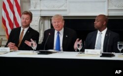 President Donald Trump, flanked by Sen. Dean Heller, R-Nev., left, and Sen. Tim Scott, R-S.C.,speaks at a luncheon with GOP leadership, July 19, 2017, in the State Dinning Room of the White House in Washington.