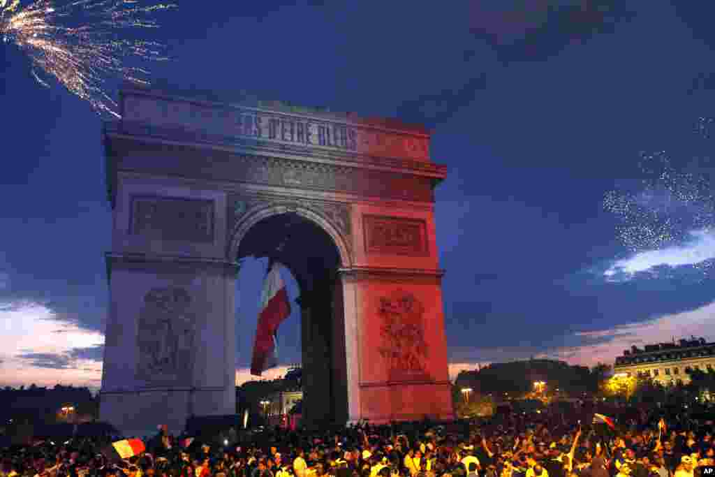 Arc de Triomphe disiram cahaya warna bendera Perancis dan kembang api dinyalakan oleh para penggemar sepak bola untuk merayakan kemenangan Perancis atas Kroasia di final Piala Dunia 2018, di Paris, 15 Juli 2018. Tulisan di Arc de Triomphe terbaca: Bangga menjadi biru (Perancis)