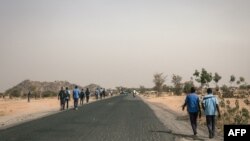Des lycéens marchent sur la route de Mokolo à Maroua, Région de l'Extrême-Nord, Cameroun, le 20 février 2018. / AFP PHOTO / ALEXIS HUGUET