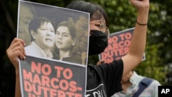 FILE - A protester holds a photo bearing the photos of the late dictator's son, Ferdinand Marcos Jr., left, and Davao city Mayor Sara Duterte during a protest outside the Commission on Human Rights in Quezon city, Philippines, Nov. 14, 2021.