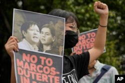 Seorang pengunjuk rasa memegang foto yang memuat foto putra mendiang diktator, Ferdinand Marcos Jr., kiri, dan Wali Kota Davao Sara Duterte selama protes di luar Komisi Hak Asasi Manusia di kota Quezon, Filipina, 14 November 2021. (Foto: : AP)