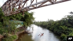 FILE - A youth jumps from an overpass into a river in Paragominas, northern state of Para, Brazil, Sept. 22, 2011. A Brazilian judge on Wednesday granted an injunction blocking a decree by President Michel Temer that opens up a vast Amazon area to mining.
