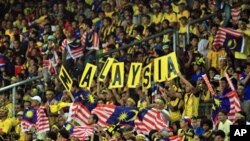 Malaysia football fans hold up national flags during the AFF Cup 2010 first leg finals football final match held at the Bukit Jalil National Stadium in Kuala Lumpur, Dec. 26, 2010.
