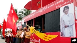 Supporters holding flags of Myanmar opposition leader Aung San Suu Kyi's National League for Democracy party stand as a Myanmar artist sings a song on campaign truck during an election campaign in Yangon, Oct. 7, 2015.